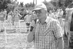 Stanisław z mikrofonem na tle ludzi prowadzi pokaz maszyn na Dniach Pola w Grubnie